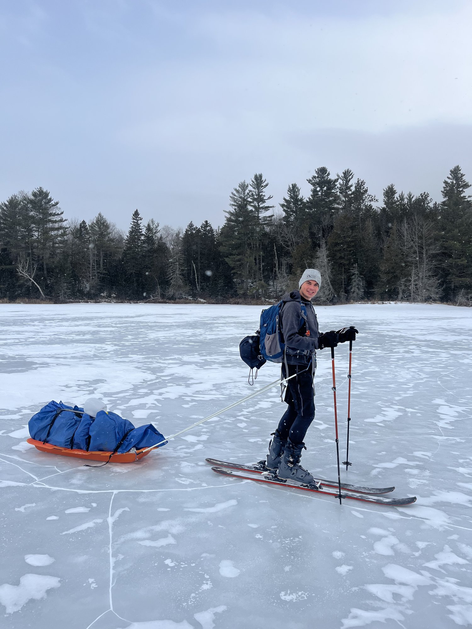 Skiing across a frozen lake, pulling a gear sled